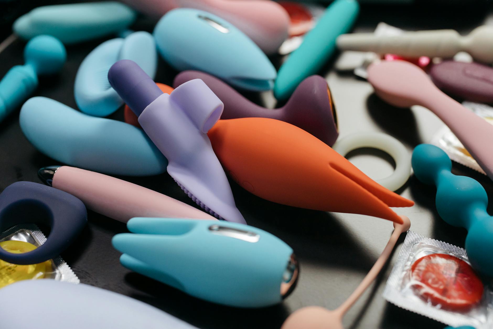 Close-up of a woman holding a pink vibrator, with art books in the background, emphasizing intimate and personal themes.