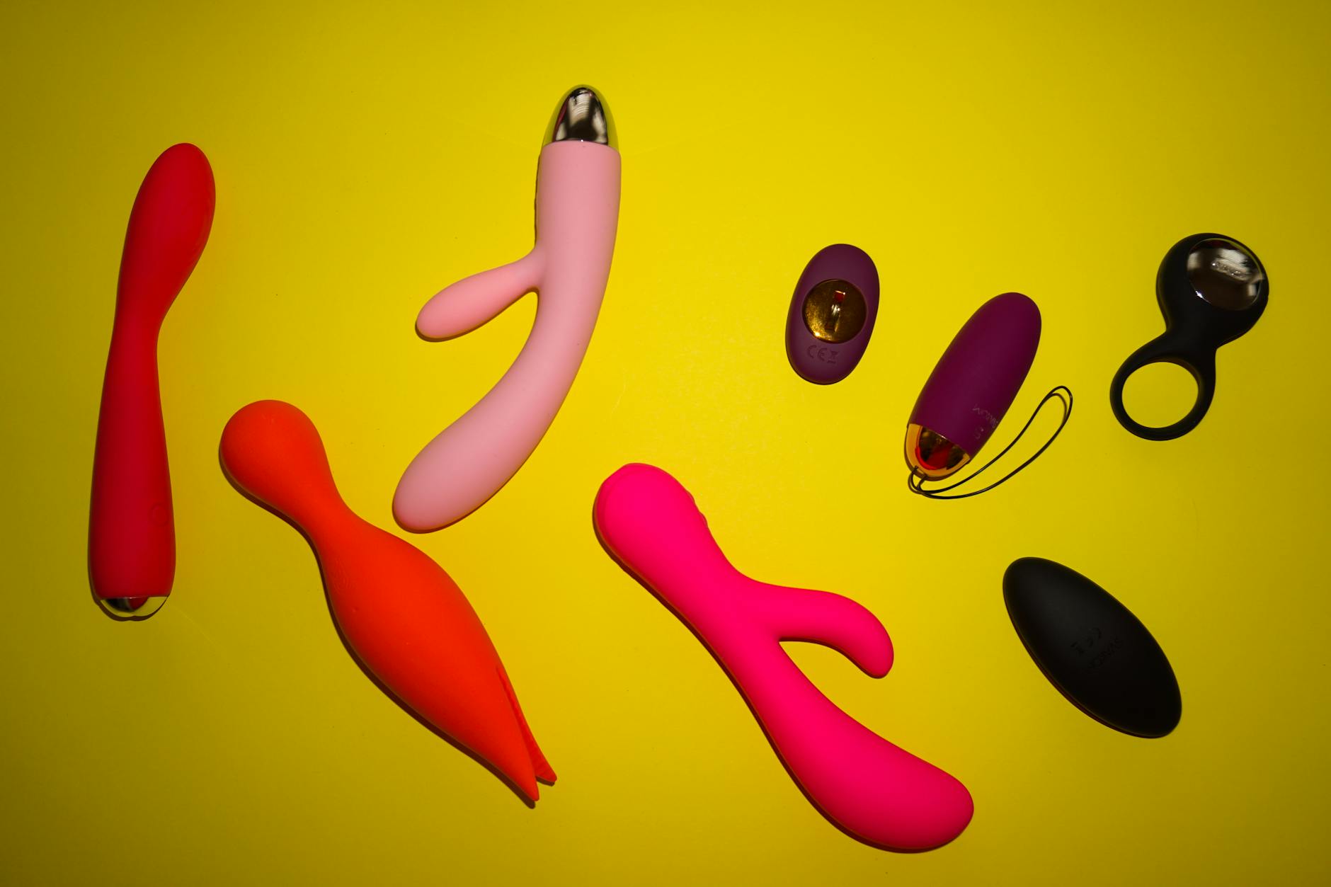 Vibrant collection of colorful sex toys on a bright yellow surface, showcasing lemon vibrators and other devices